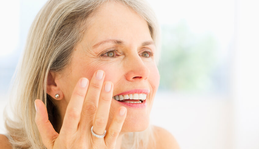 A mature woman checking for dark spots on face